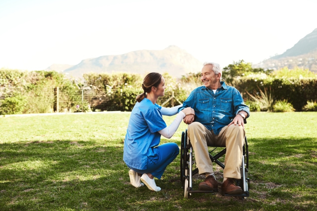 A caregiver kneels by an older client in a wheelchair, representing respite care in Orange, VA.